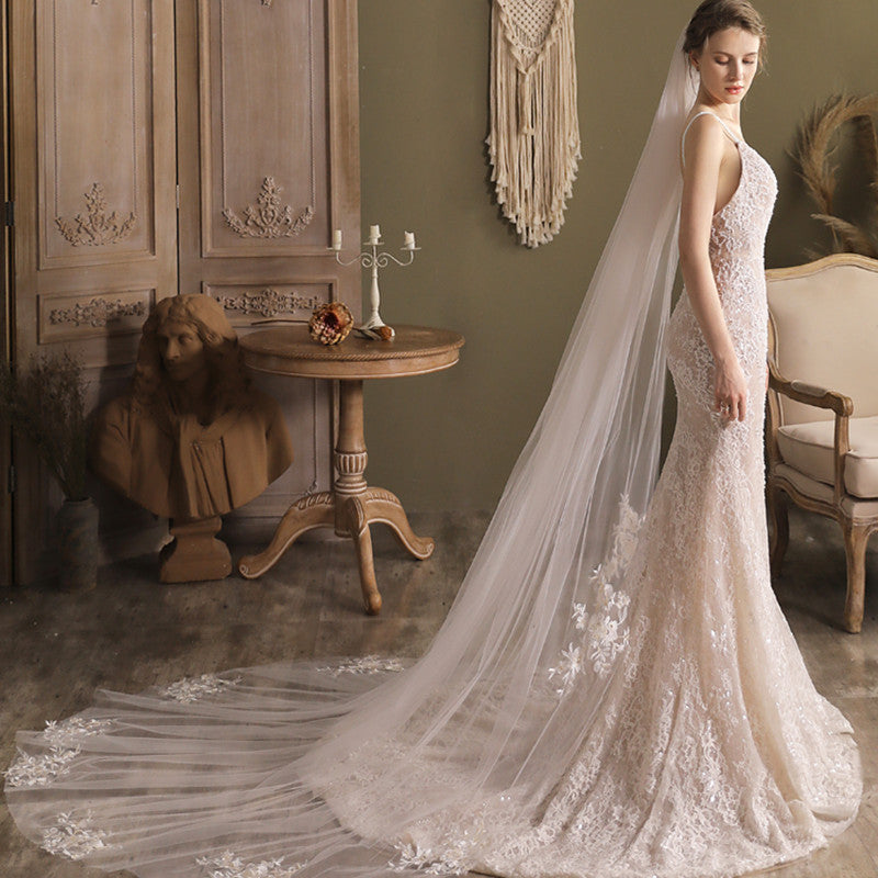 Woman in a wedding dress with a long veil standing in an elegant room.