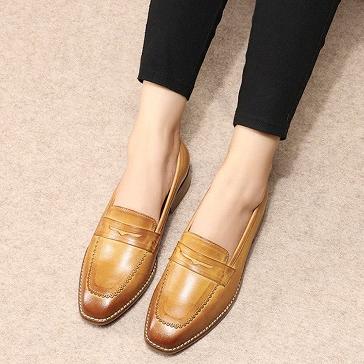 Brown loafers worn with black pants on a beige carpet