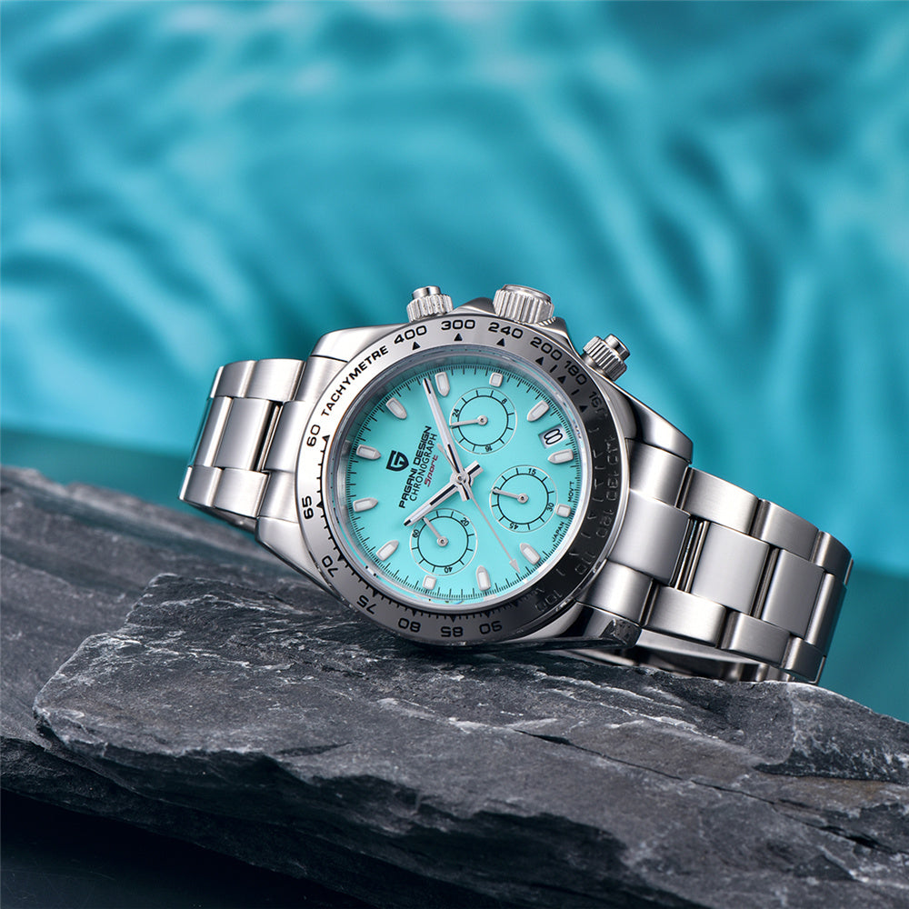 Silver watch with a turquoise face on a dark rock with a blue water background