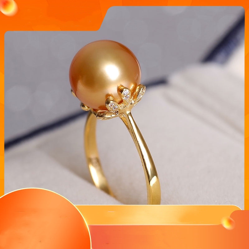 Gold ring with a large pearl and smaller stones on an orange and gray background