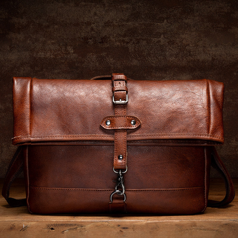 Brown leather bag with strap on a wooden surface and dark background