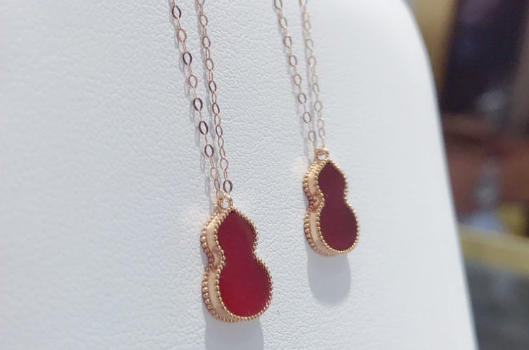 Red teardrop-shaped pendants on gold chains against a white background