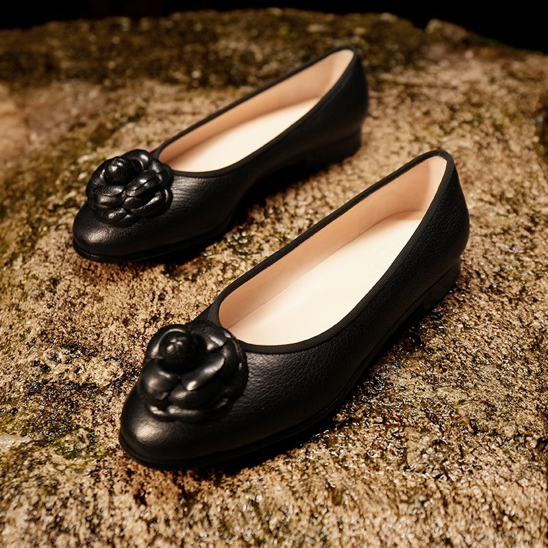 Pair of black shoes with floral designs on a textured surface
