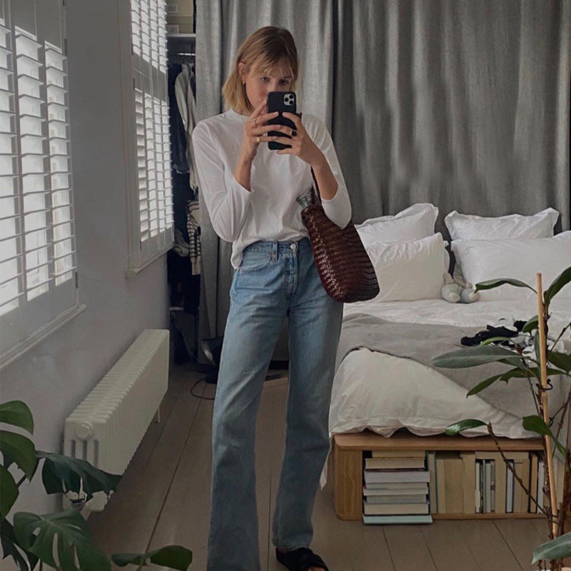 Person taking a mirror selfie in a bedroom with a bed and plants.