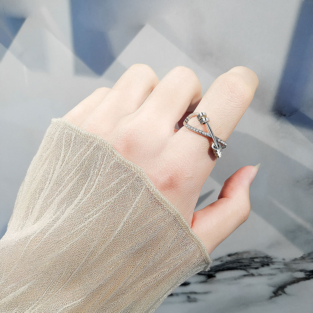 Hand wearing a silver ring with a textured sleeve on a marble surface