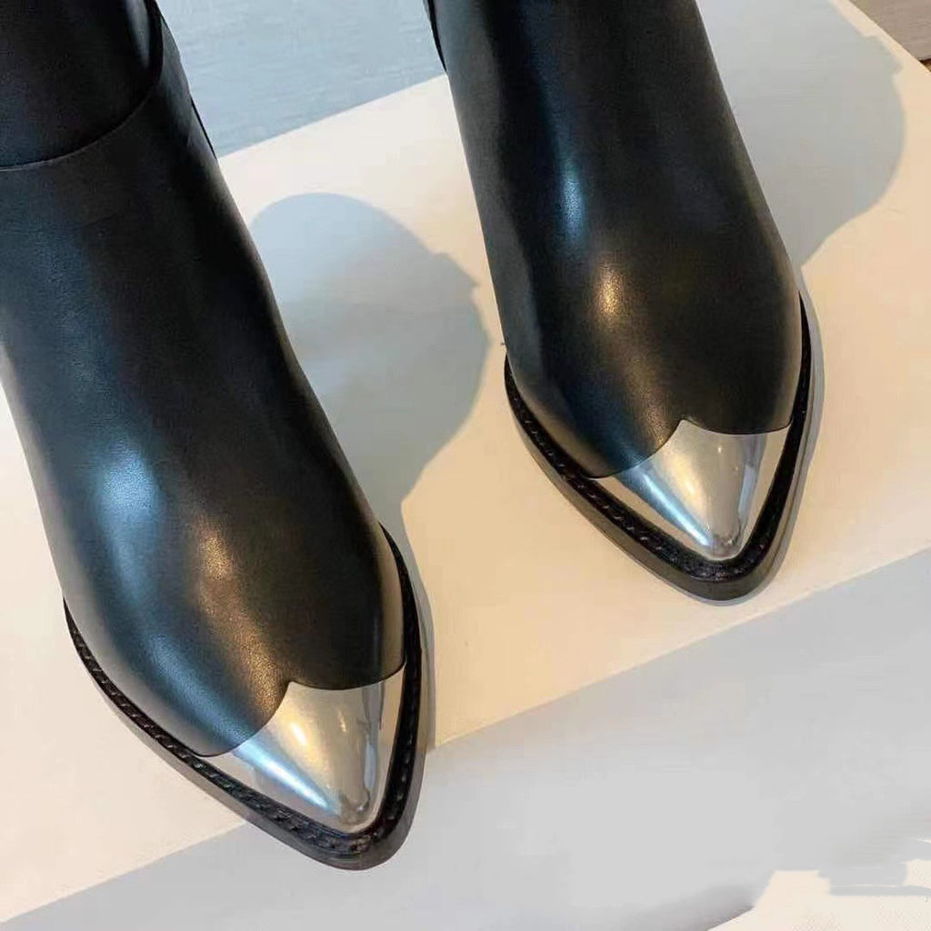 Black leather boots with metallic tips on a light background