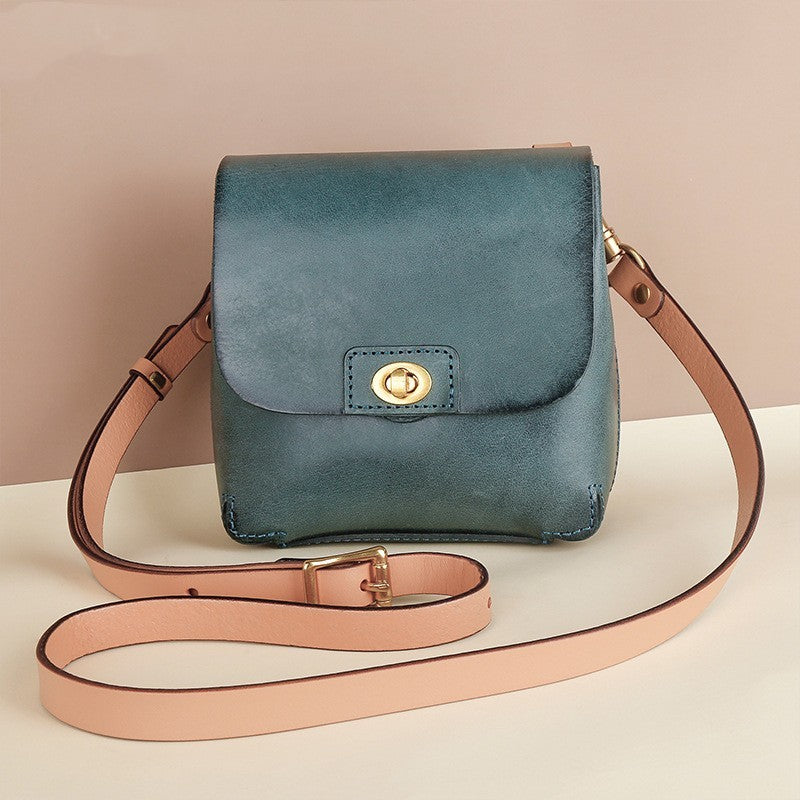 Blue leather handbag with a beige strap on a light background