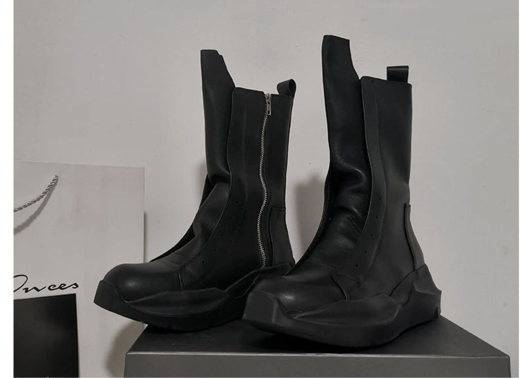 Pair of black leather boots on a gray surface with a white background