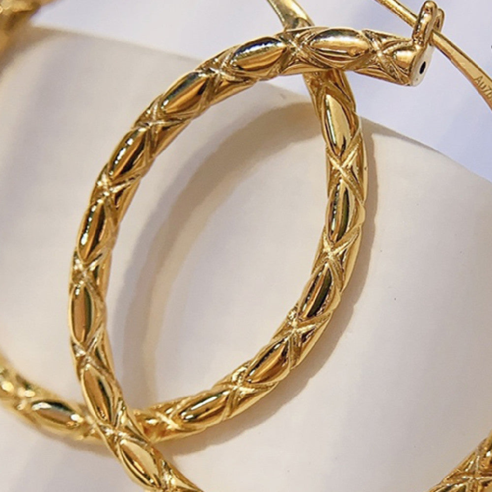 Gold hoop earrings with intricate design on a white background