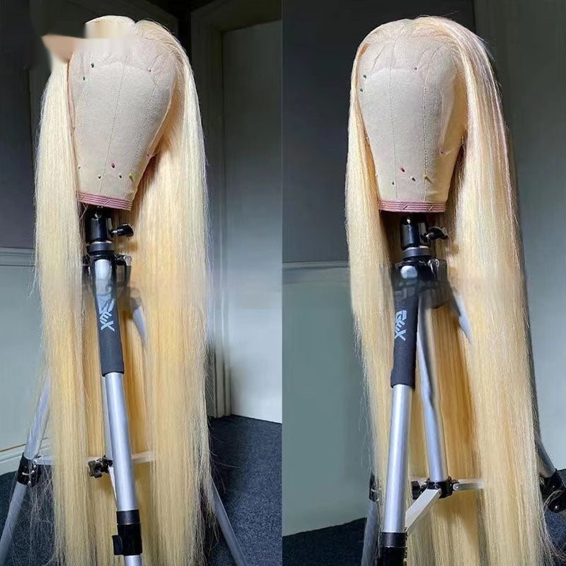 Blonde wig on a mannequin head with a stand against a neutral background