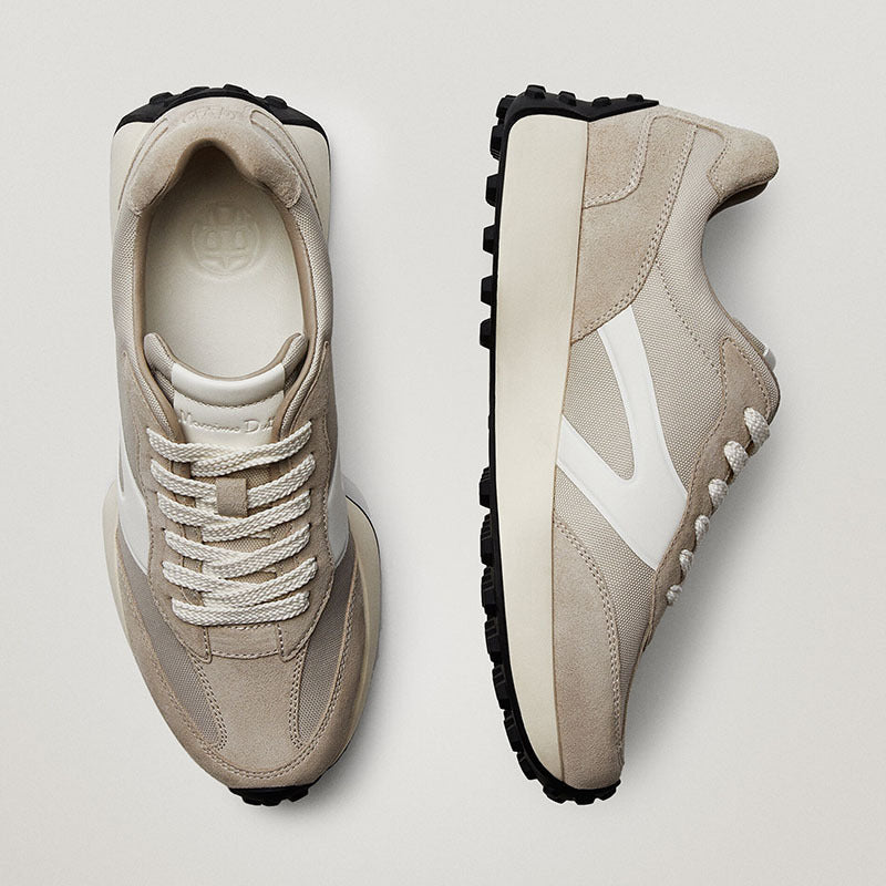 Pair of beige sneakers with white accents on a light gray background