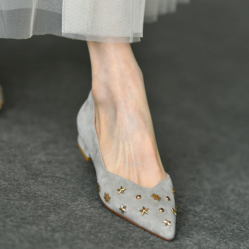 Gray suede shoe with gold star embellishments on a dark gray background