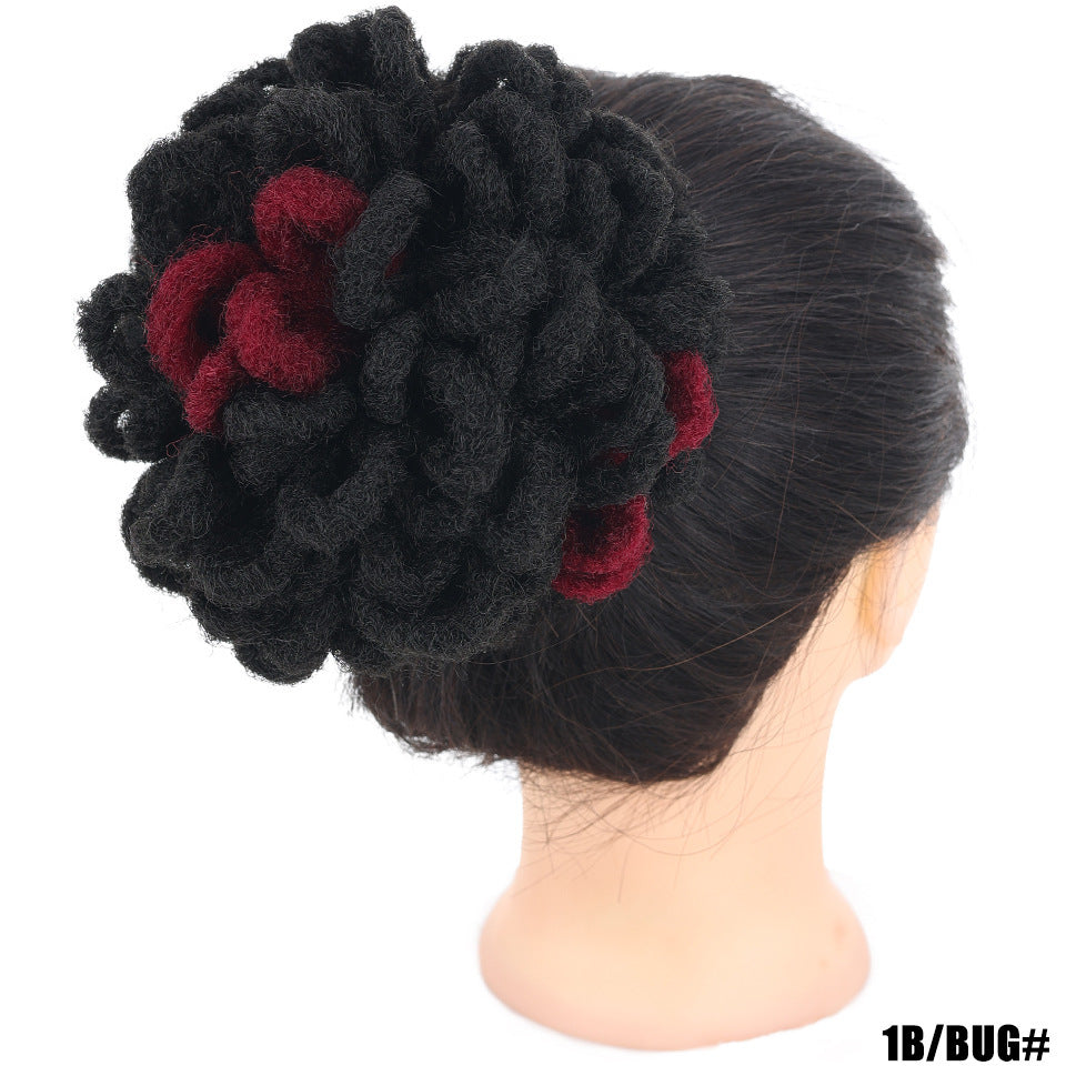 Black flower hair accessory with red centers on a mannequin head against a white background