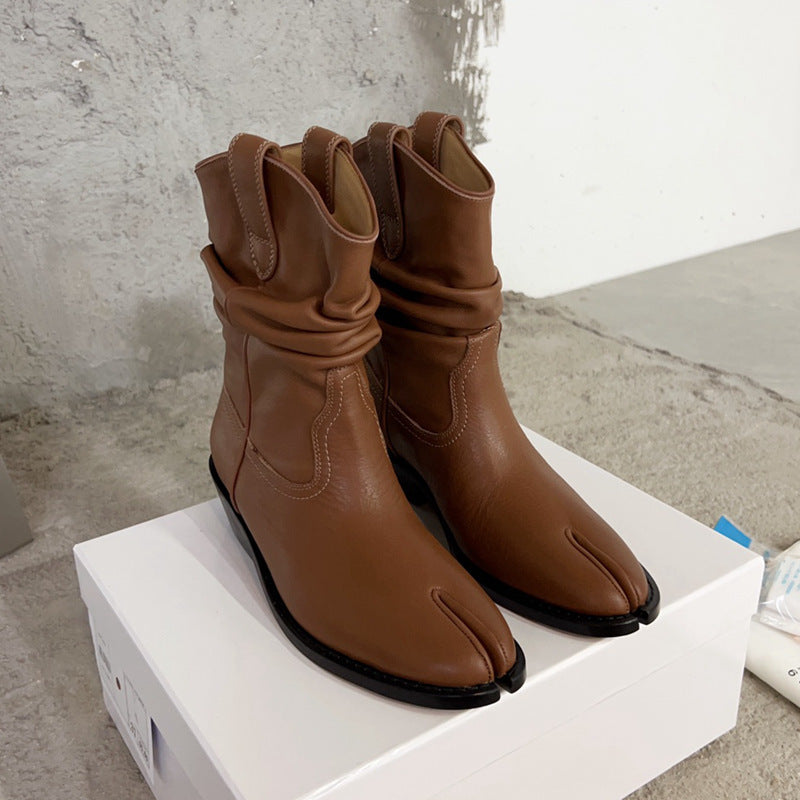 Pair of brown tabi boots on a white platform with a concrete floor background