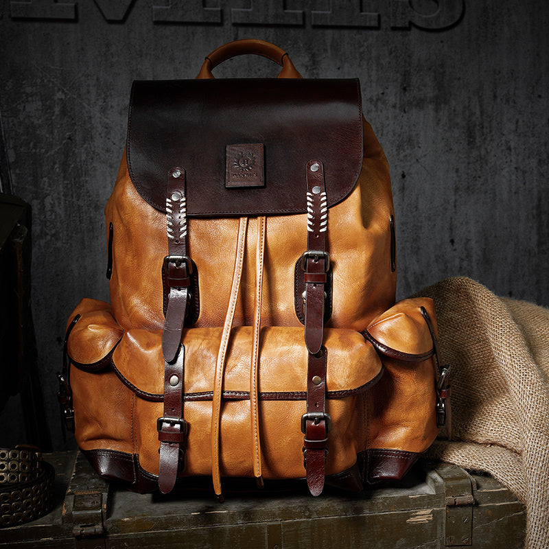 Brown leather backpack with black top section on a dark background