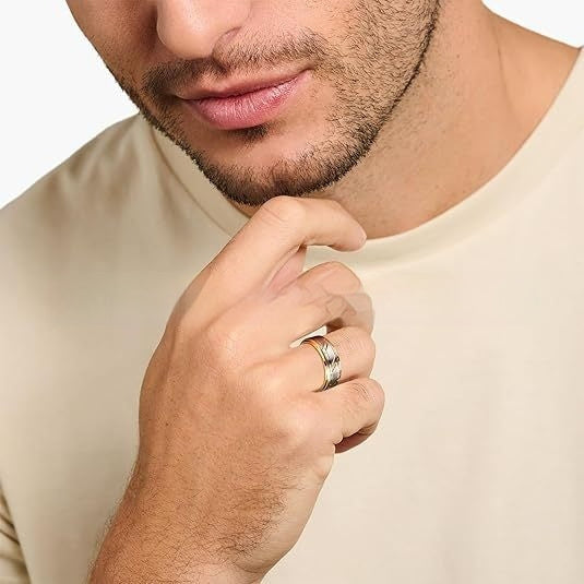 Man wearing a gold ring on his finger against a neutral background