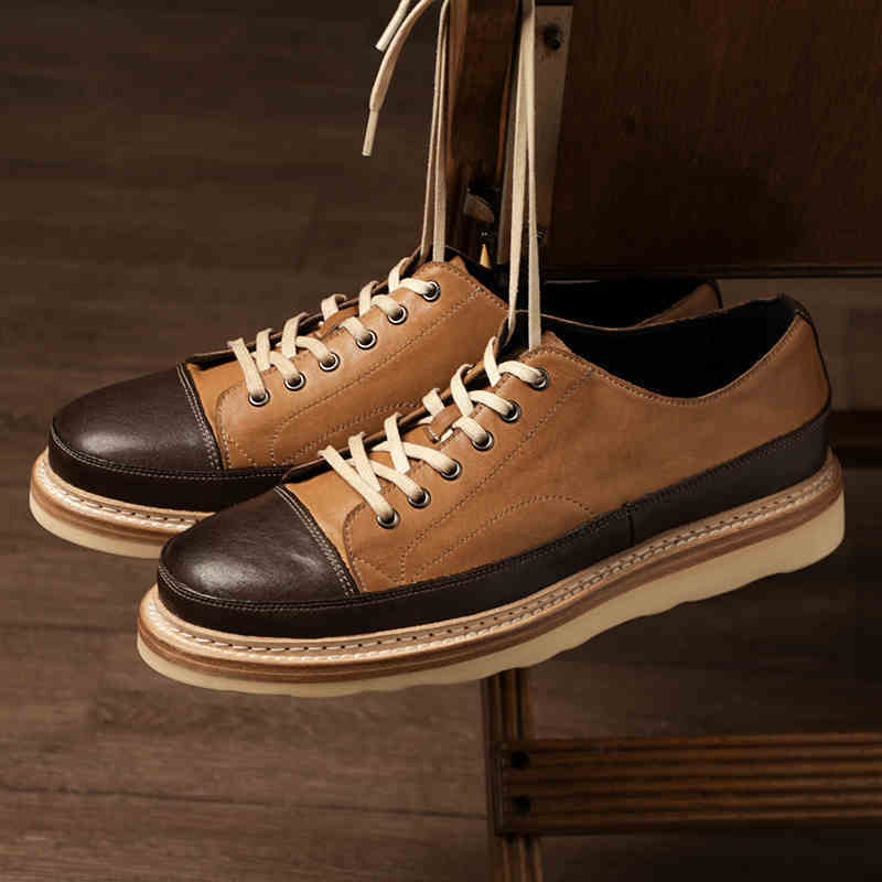 Brown and black sneakers with white laces on a wooden surface
