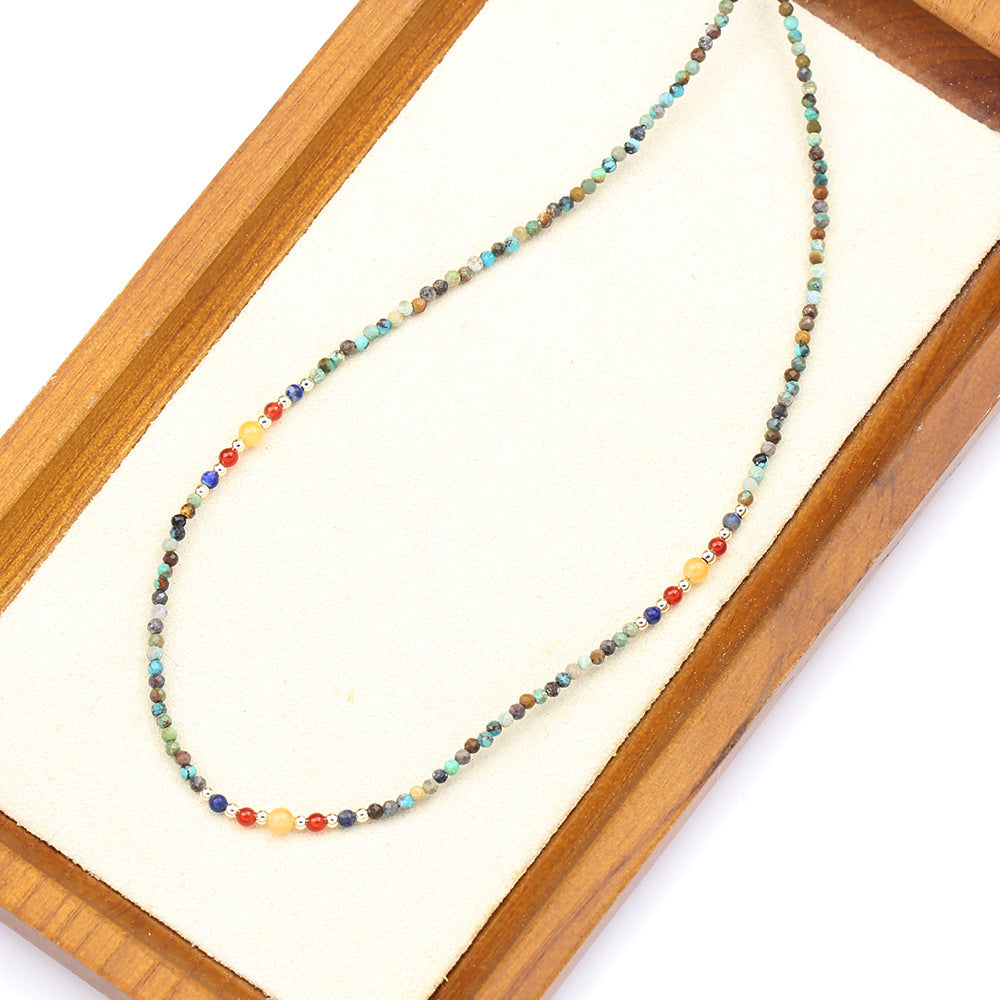Multicolored beaded necklace on a wooden tray with a white background