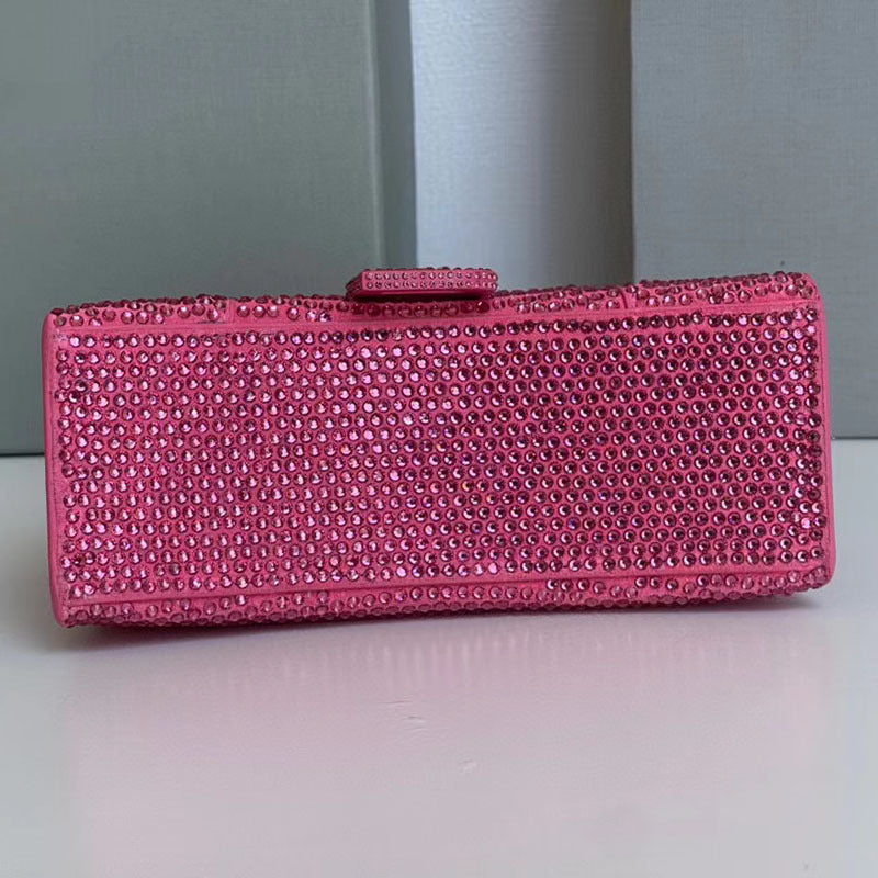 Pink clutch bag with rhinestone detailing on a light gray background