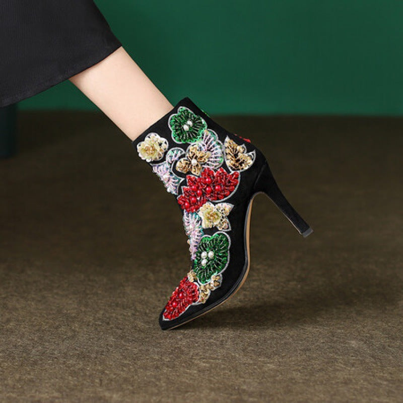 Black high-heeled shoe with colorful floral embroidery on a dark background