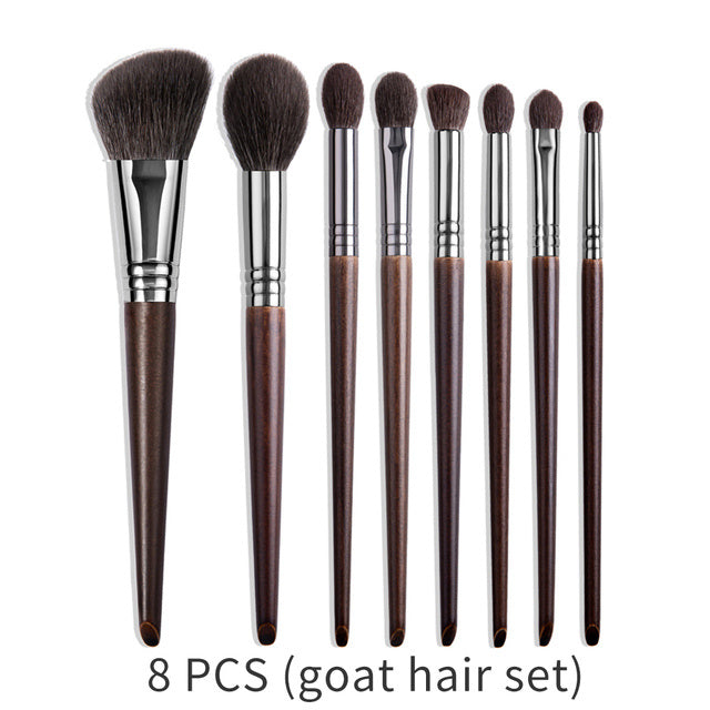 Set of eight makeup brushes with brown handles and black bristles on a white background.