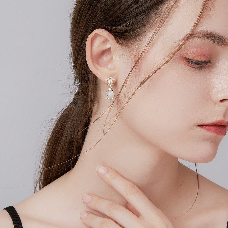 Close-up of a woman wearing elegant earrings with a neutral background