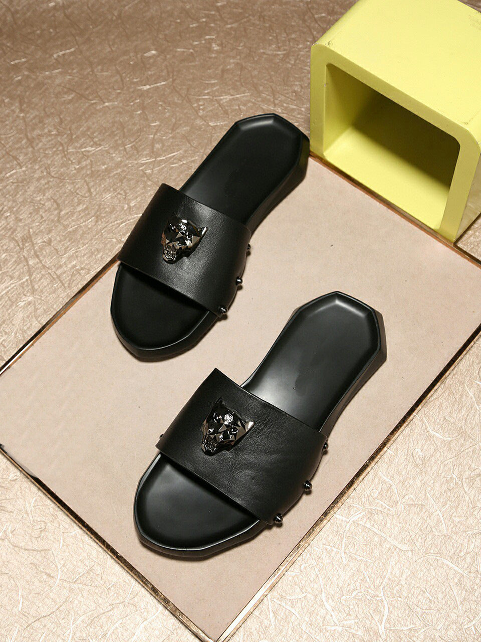 Black sandals with decorative elements on a beige surface