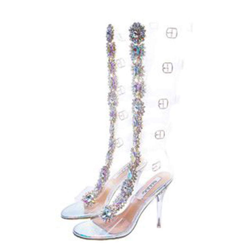 Clear high-heeled shoes with colorful bead embellishments on a white background
