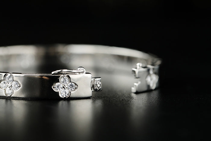 Silver bracelet with clover-shaped ends on a black background