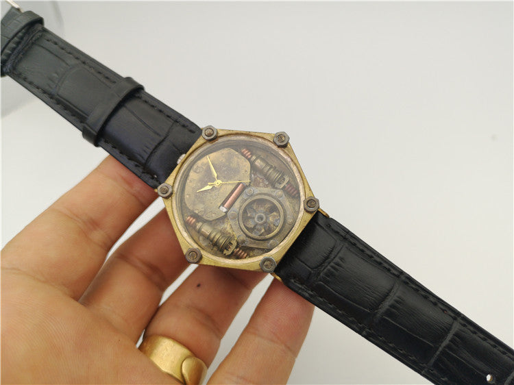 Vintage-style watch with black leather strap held by a hand against a white background