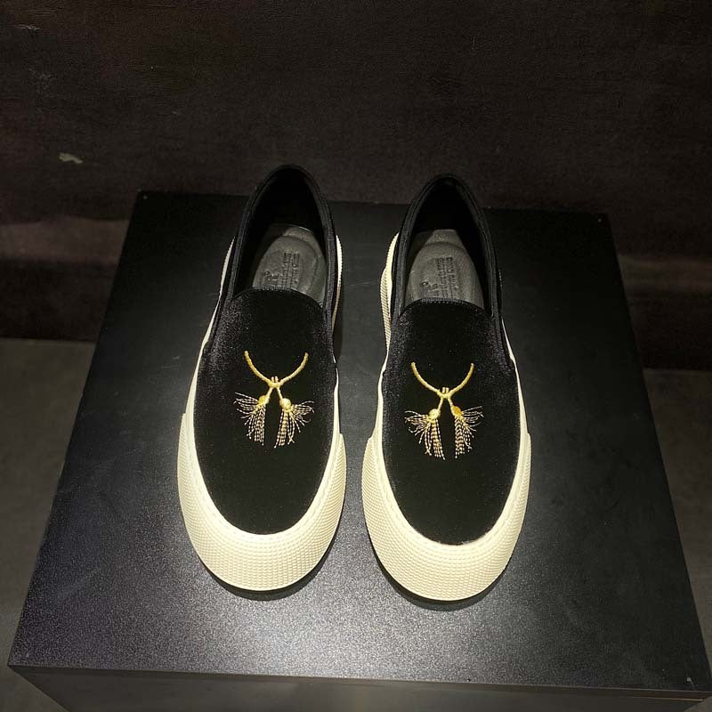 Black loafers with gold embroidery on a dark surface