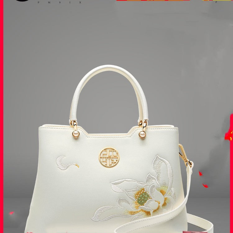 White handbag with floral embroidery on a gray background