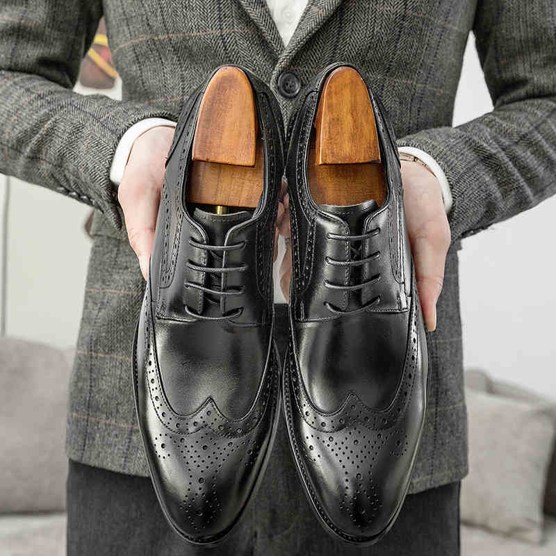 Person holding two black leather dress shoes with wooden soles.