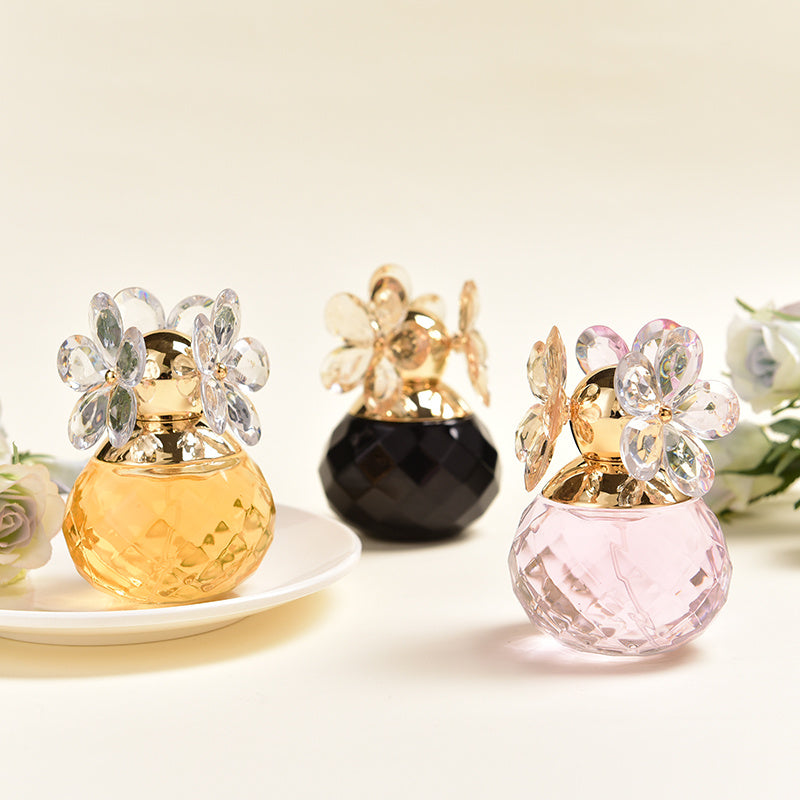 Three decorative perfume bottles with floral designs on a light background