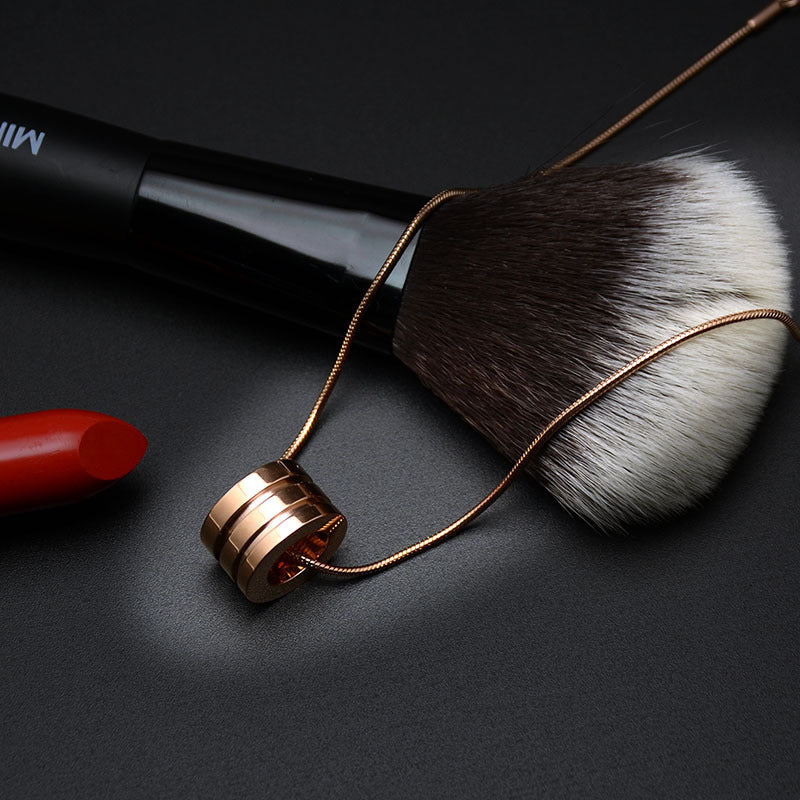 Makeup brush with rose gold handle and red lipstick on black background