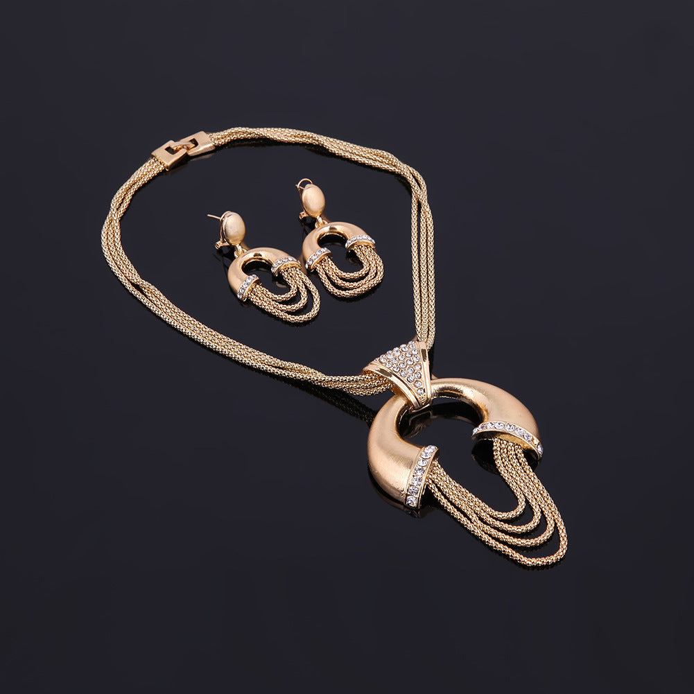 Gold necklace and earrings set on a dark background