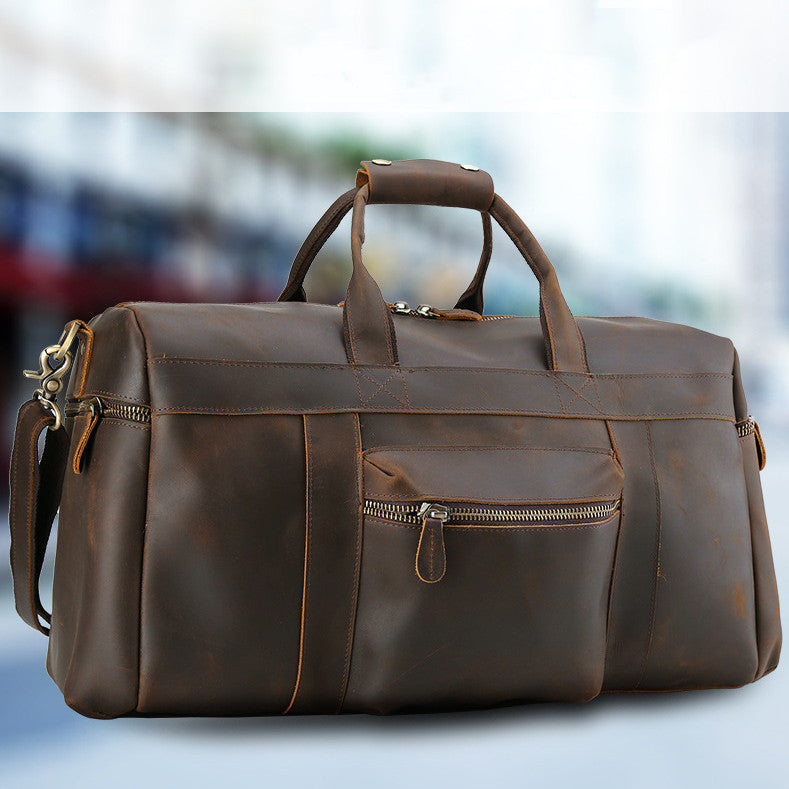Brown leather duffel bag with zippers on a blurred background