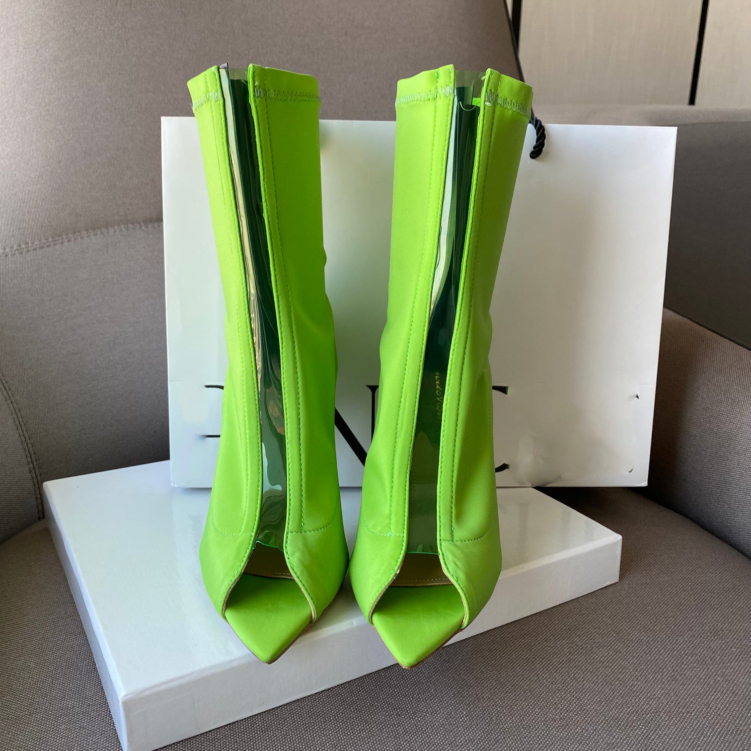 Green high-heeled boots on a white platform with a neutral background