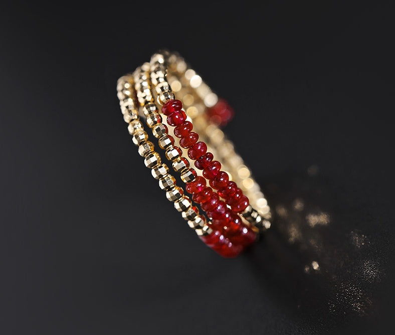 Gold and red beaded bracelet on a dark background