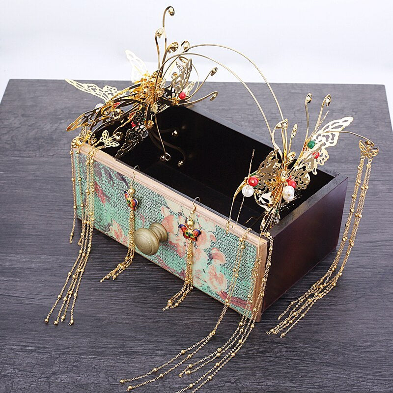 Decorative gold headpiece with butterfly details on a wooden box