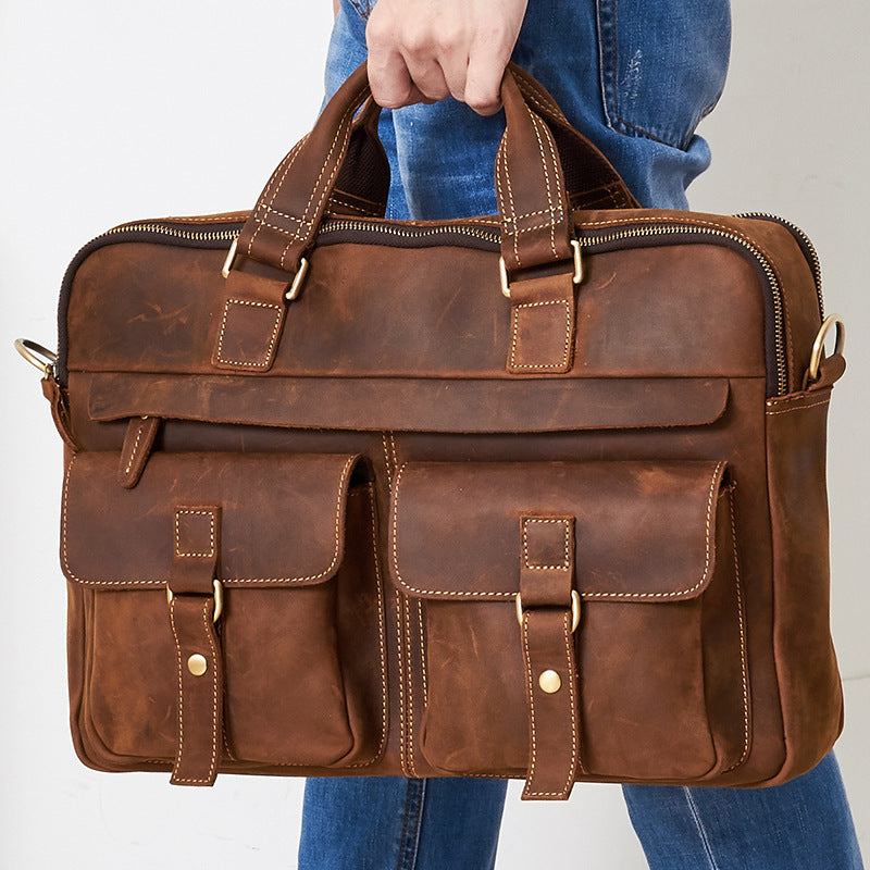 Brown leather briefcase held by a person wearing blue jeans on a white background