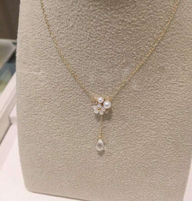 Delicate gold necklace with a floral pendant on a neutral background