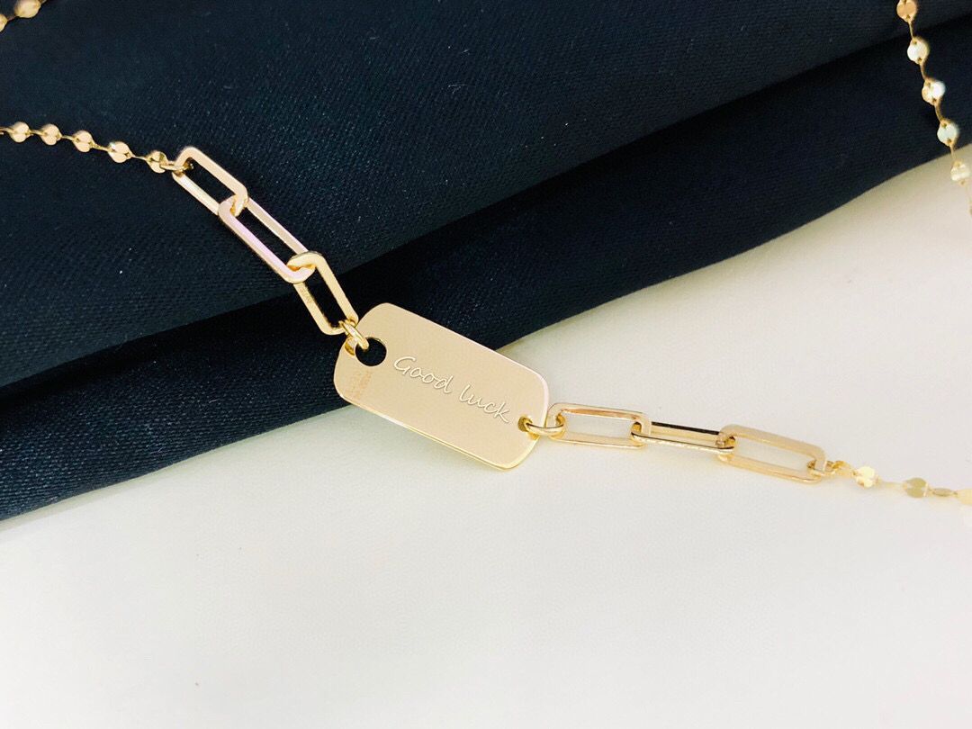 Gold bracelet with a tag on a dark blue fabric background