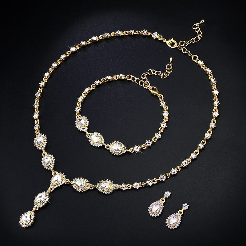 Gold jewelry set with necklace, bracelet, and earrings on a black background