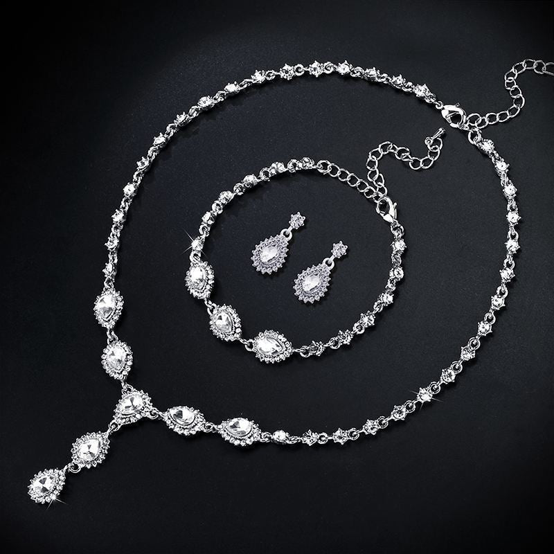Silver jewelry set with necklace, bracelet, and earrings on a black background