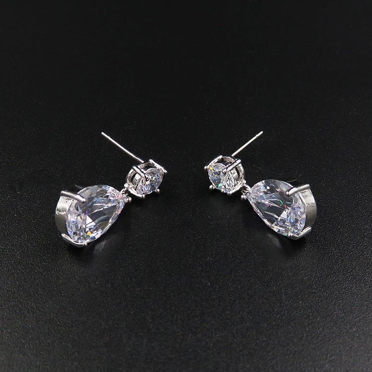 Pair of silver earrings with clear gemstones on a black background