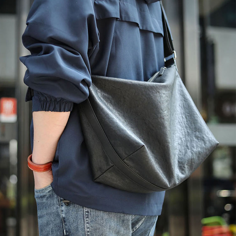 Person wearing a blue jacket with a gray shoulder bag in an urban setting