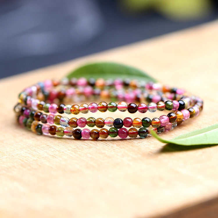 Multicolored beaded bracelet on a wooden surface with a blurred natural background