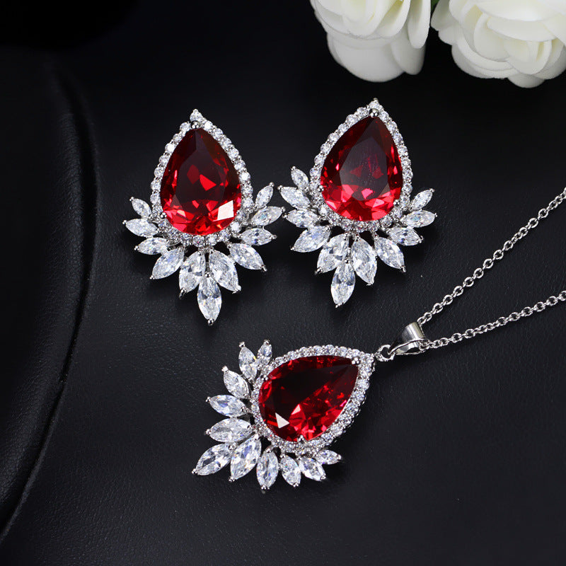 Jewelry set with red teardrop gemstones on a black background