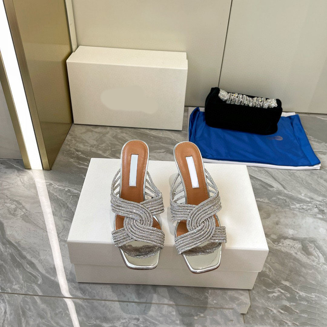Pair of silver strappy sandals on a white box with a blurred background